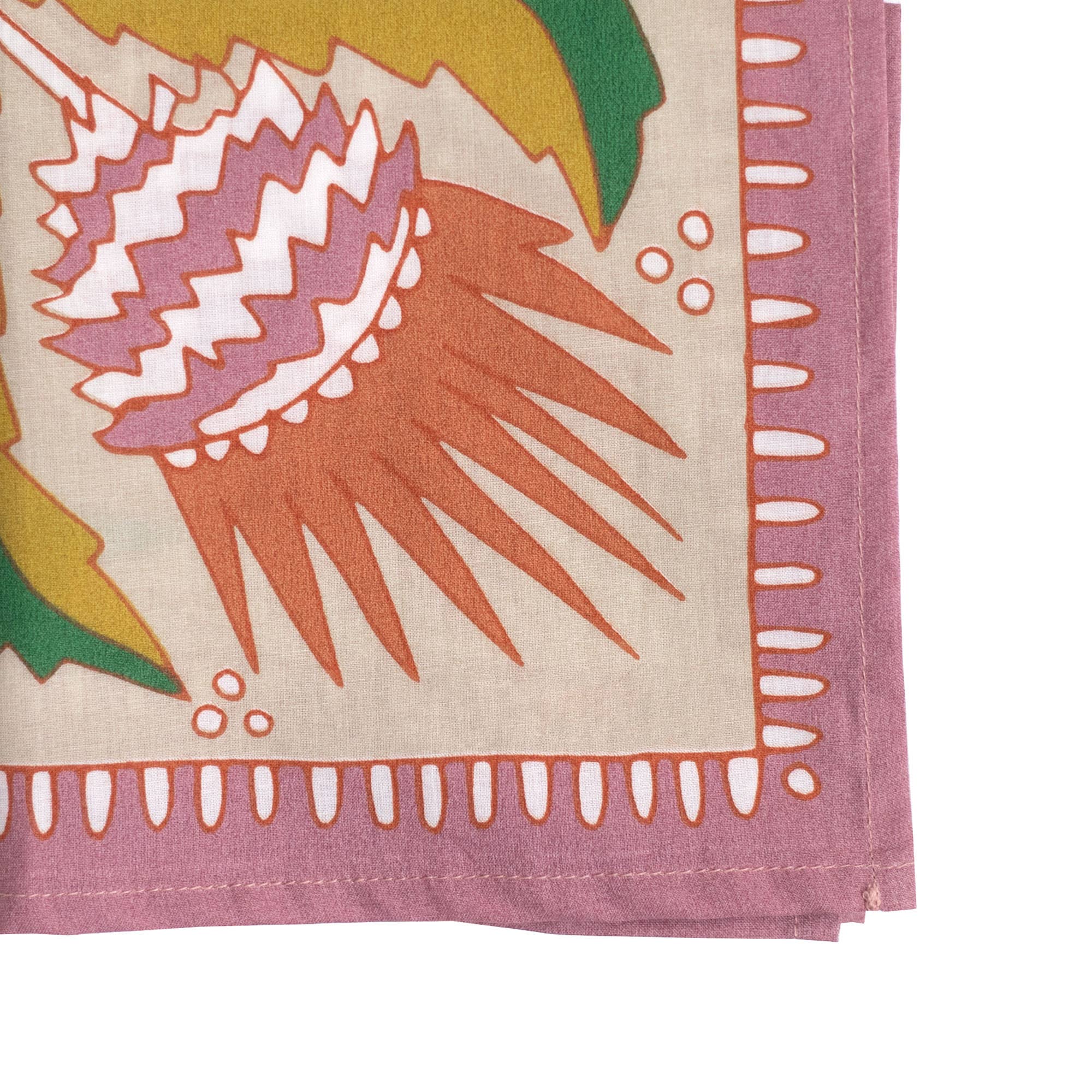 A close-up of the No. 081 Martha Bandana by Handker Bandanas, featuring premium cotton, a pink border, and a vibrant abstract design with spiky orange and white details alongside green plant-like shapes.