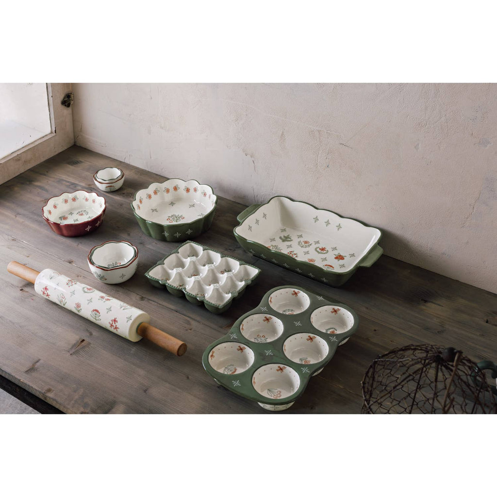 Danica Heirloom Camellia Bowl Medium 5.75 inch with other ceramic bakeware, floral bowls, and a rolling pin on a rustic wooden table near a window.