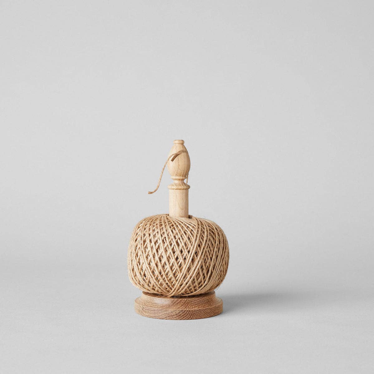 The Gardener's Planting Set by Bloomist features a spool of natural twine on a wooden base with a vertical holder and knob, ideal for use with gardening tools like floral scissors, shown against a plain light gray background.