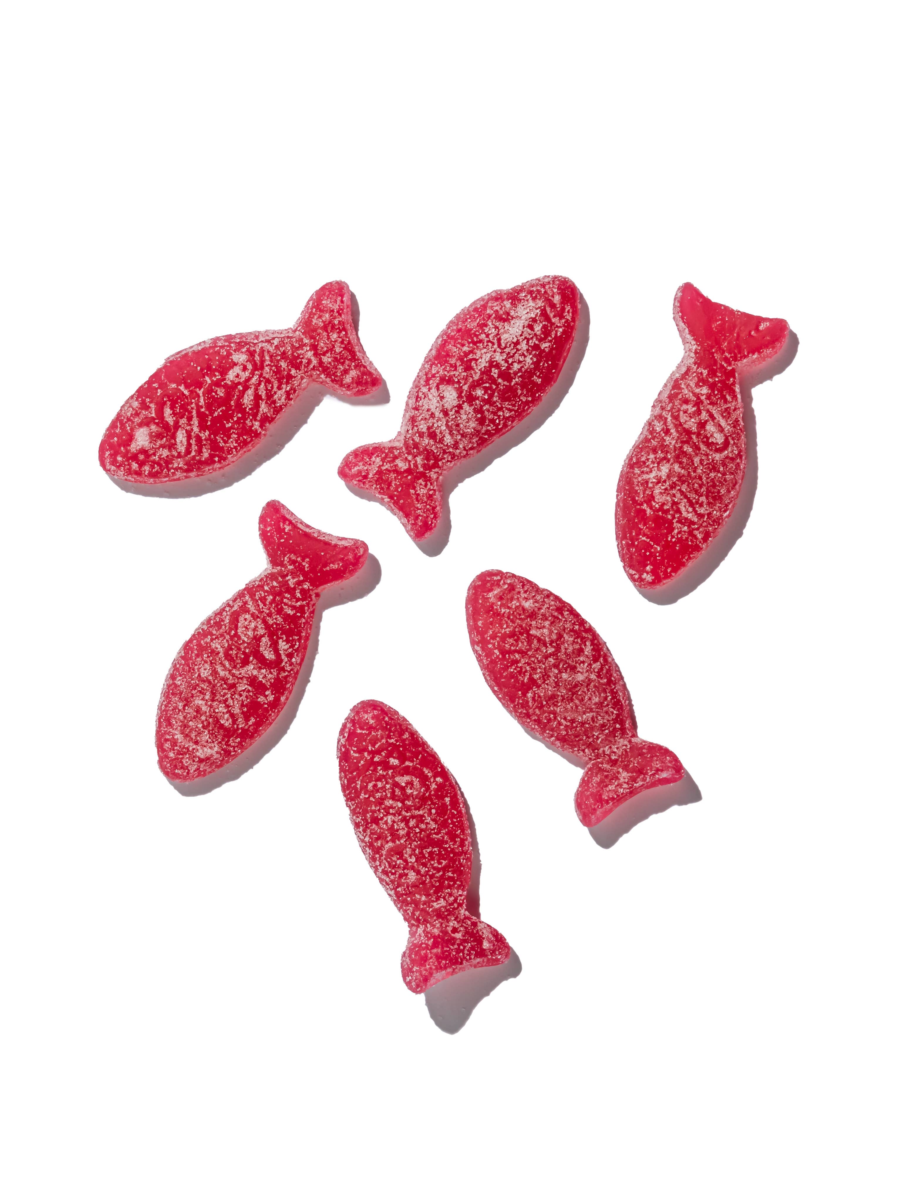 Six red, fish-shaped BonBon Sour Wild Strawberry Fish candies, sugar-coated and vegan, are arranged on a white background. Each offers a tangy wild strawberry flavor.