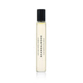 A clear glass Heretic Parfum SCANDALWOOD ROLLERBALL: 10ML perfume bottle with a black cap stands upright on a white background. The label is printed vertically, suggesting notes of sandalwood and musk.