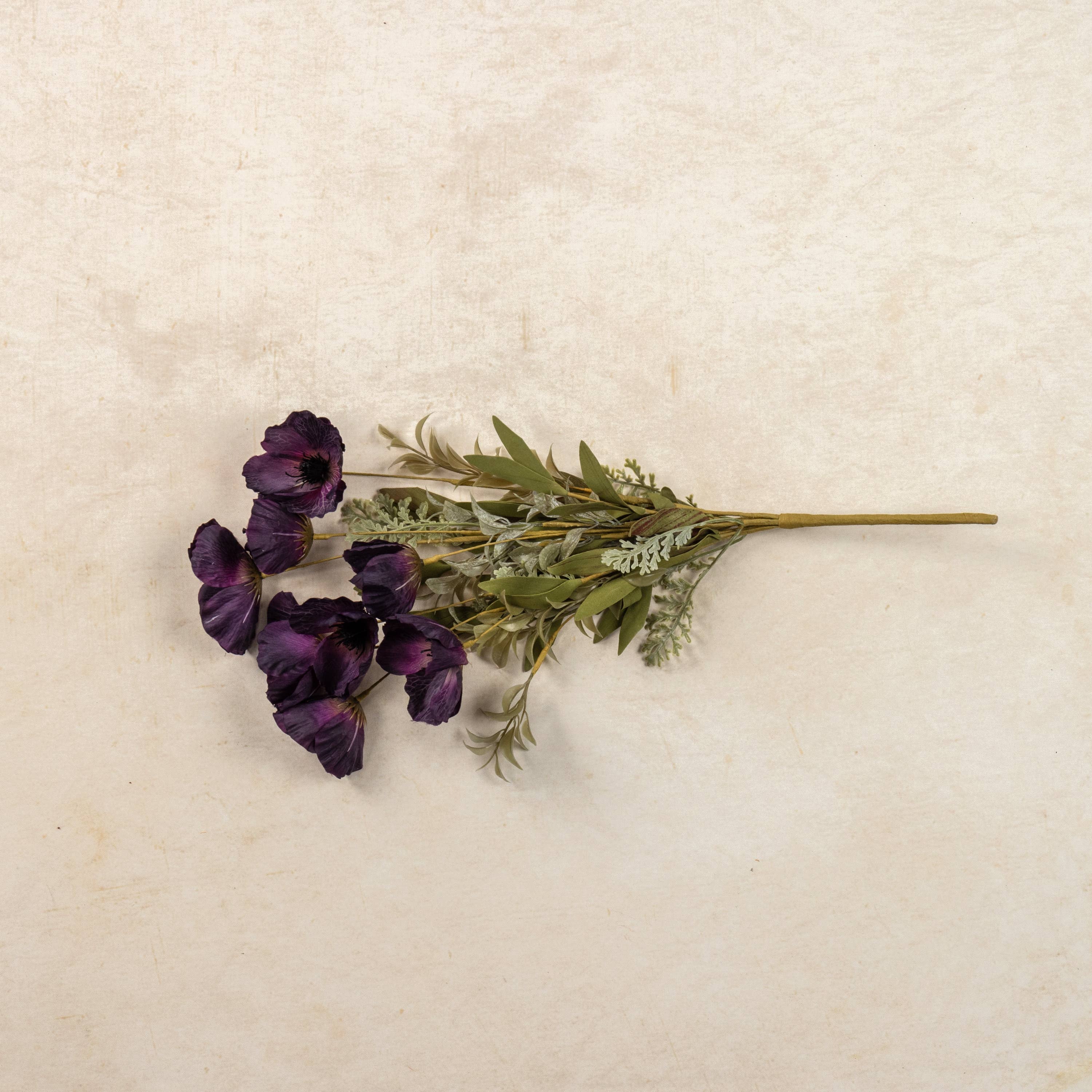 A 22" Artificial Dark Purple Poppy Bush by Ragon House, featuring vibrant blooms and green leaves, is displayed on a light beige textured surface.