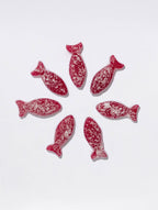 Seven sour blackberry fish candies from BonBon - A Swedish Candy Co are arranged in a circle on a white background.