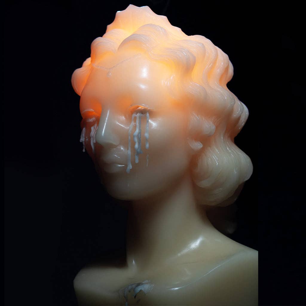 WEEPING BUST by Heretic Parfum is a limited-edition surreal candle depicting a woman’s bust with glowing light and white wax "tears" against a dark background—a striking sculptural addition to any space.