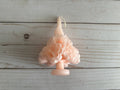 Light pink Carnation Oaxaca Marigold Day of the Dead Candle molded into the shape of a ruffled flower cluster.