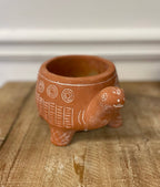 The Vagabond Vintage CEMENT RED TURTLE PLANTER (Large), crafted from cement with geometric patterns, rests empty on a wooden surface against a neutral background.