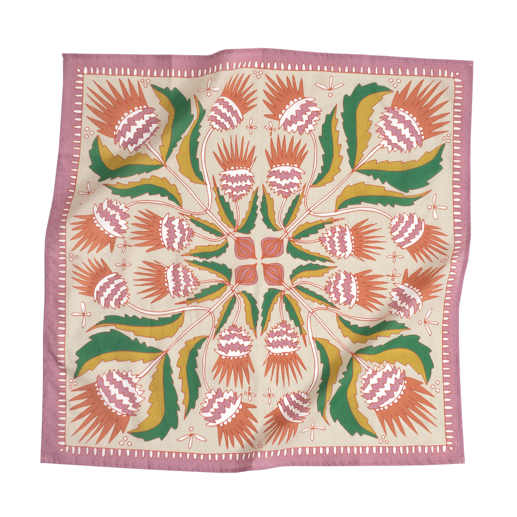The No. 081 Martha Bandana by Handker Bandanas is a premium cotton square scarf with a pink border, featuring a symmetrical screen-printed floral and leaf design in soft hues radiating from the center.