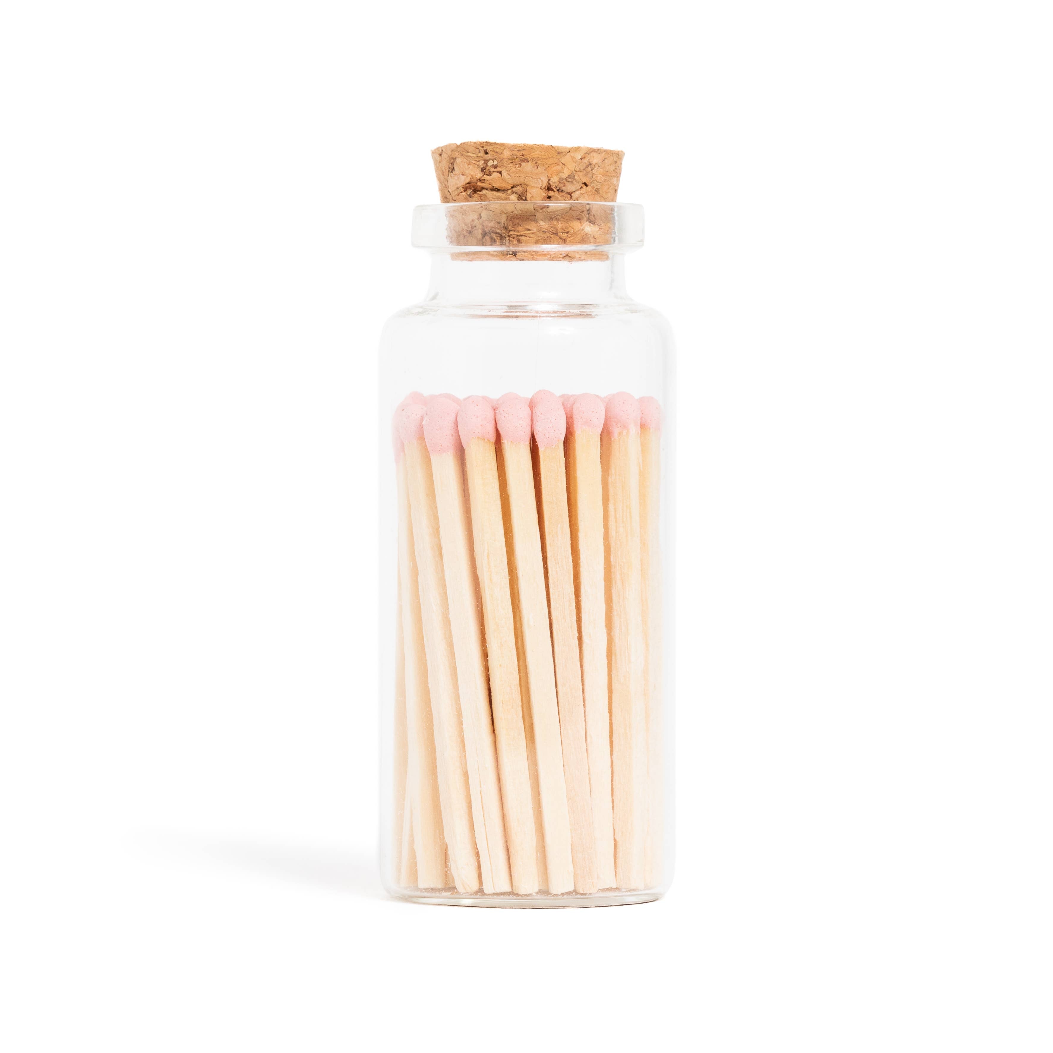 The Pink Matches in Corked Vial by Enlighten the Occasion features several pink-tipped wooden matches neatly arranged in a small glass jar with a cork stopper, displayed against a white background.