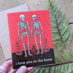 A hand holds the ilikesara "I love you to the bone" greeting card—a skeleton-themed Valentine or Halloween card, perfect for expressing dark romantic love.
