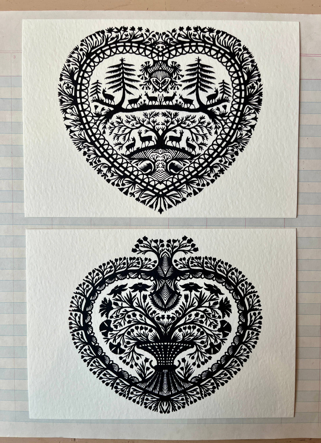 Parcel’s Papercut Heart Art Cards set features two 5x7 intricate black paper cuttings: one heart-shaped with trees, animals, and florals; the other with a central tree and floral motifs. Each comes with a creamy white envelope.