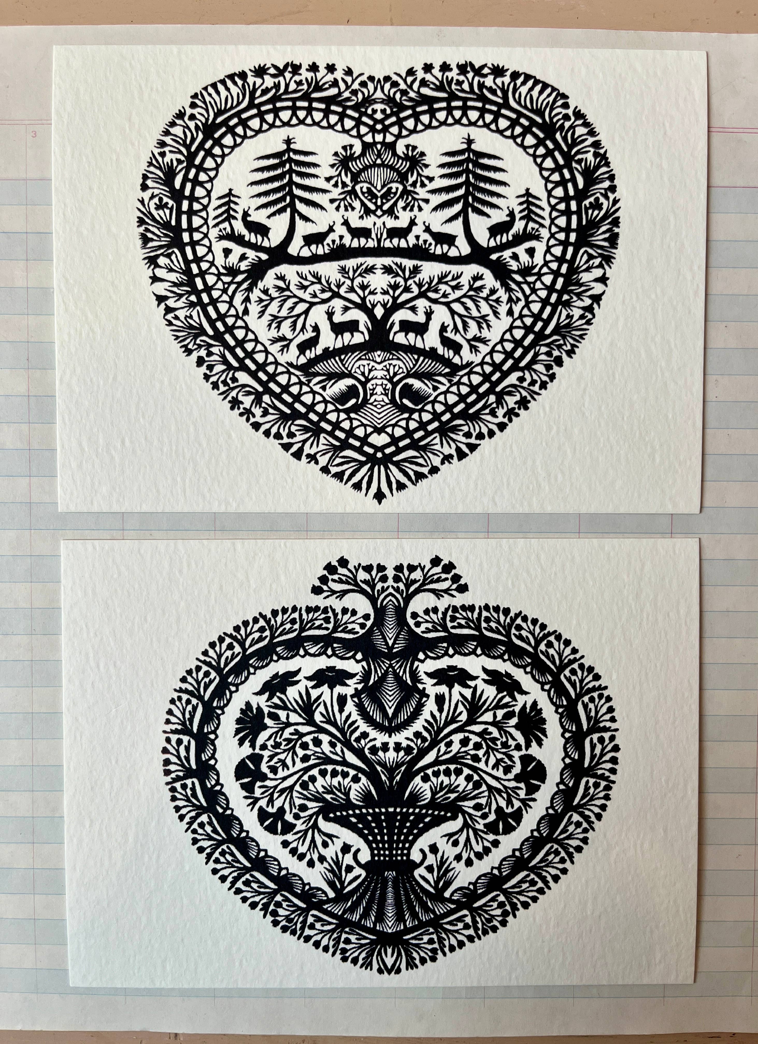 Parcel’s Papercut Heart Art Cards set features two 5x7 intricate black paper cuttings: one heart-shaped with trees, animals, and florals; the other with a central tree and floral motifs. Each comes with a creamy white envelope.