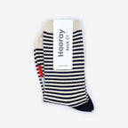 The Cole Black and White Striped Crew Socks by Hooray Sock Co. feature crew length, cream-colored toes and heels, and come partially wrapped in a white label with the brand’s name in large gray letters for unisex comfort and style.