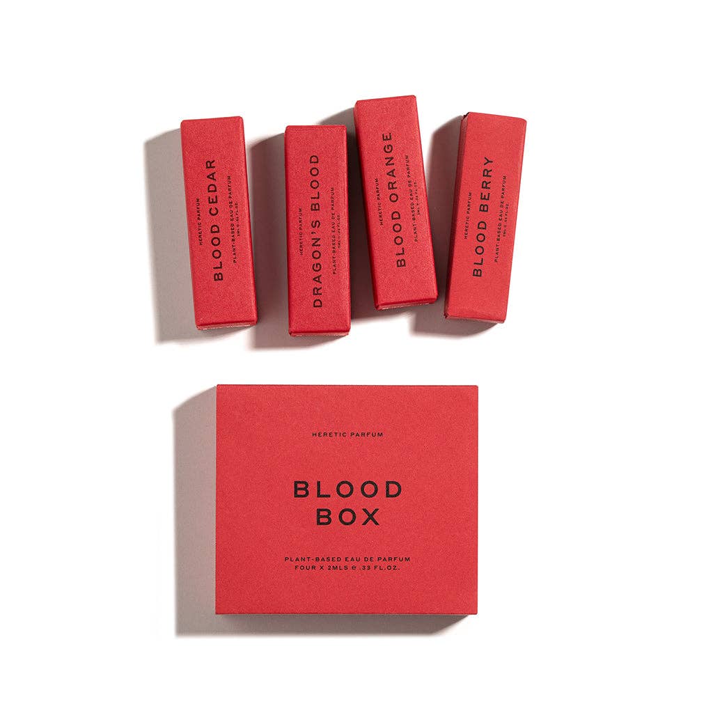 Four red perfume boxes labeled Blood Cedar, Dragon's Blood, Blood Orange, and Blood Berry are arranged above a larger red box labeled THE BLOOD BOX by Heretic Parfum—an immersive fragrance set of blood-inspired scents against a white background.