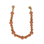 The Foreside Home & Garden Clay Garland Terracotta + Jute features hand-formed round reddish-brown clay beads in varying sizes, arranged in a U-shape with tan jute tassels tied at each end.