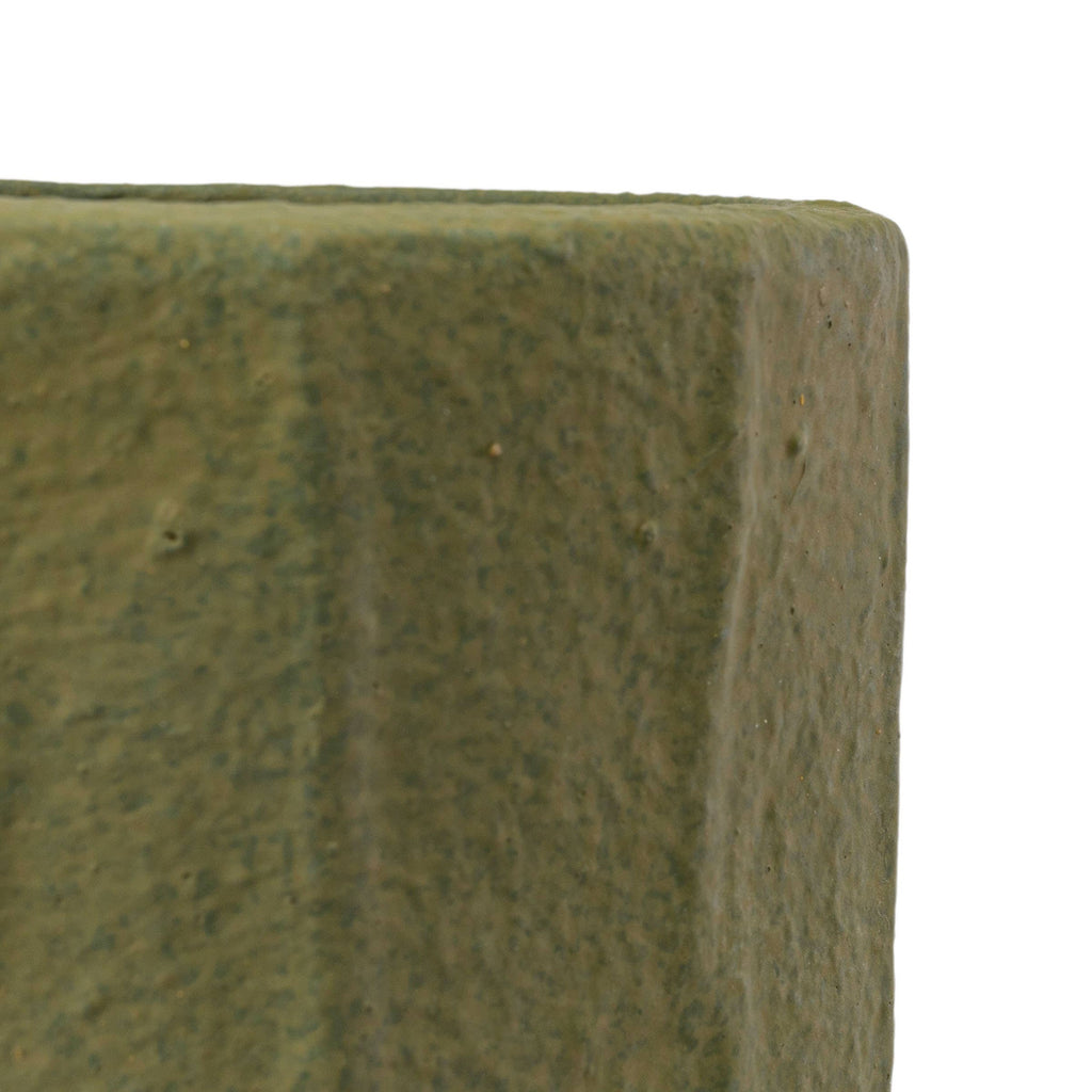 Close-up of the corner of a Foreside Home & Garden Matte Green Ceramic Pot Small, showing its textured surface against a white background.