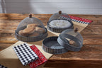 The Park Designs Covington Screen Covers with Bases (Set of 3) display bread, white napkins, and offer an empty tray on a wooden table, each protected by a mesh dome; checkered and red fabric napkins are folded nearby.