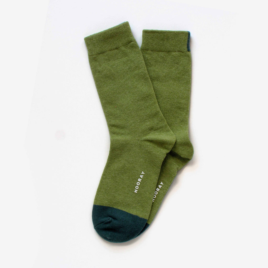 A pair of Lafayette Moss Green Crew Socks by Hooray Sock Co., unisex and one size, featuring dark green toes and "HOORAY" printed in white near the sole, arranged overlapping on a white background.