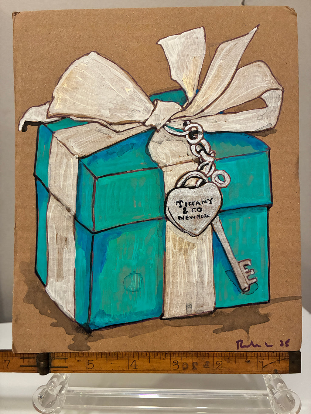 Rachel Nelson • Tiffany by Thyne Goods: Painting of a Tiffany blue gift box with white bow, silver key tag reading “Tiffany & Co. New York,” artist-signed and set on plain background with ruler at the bottom.