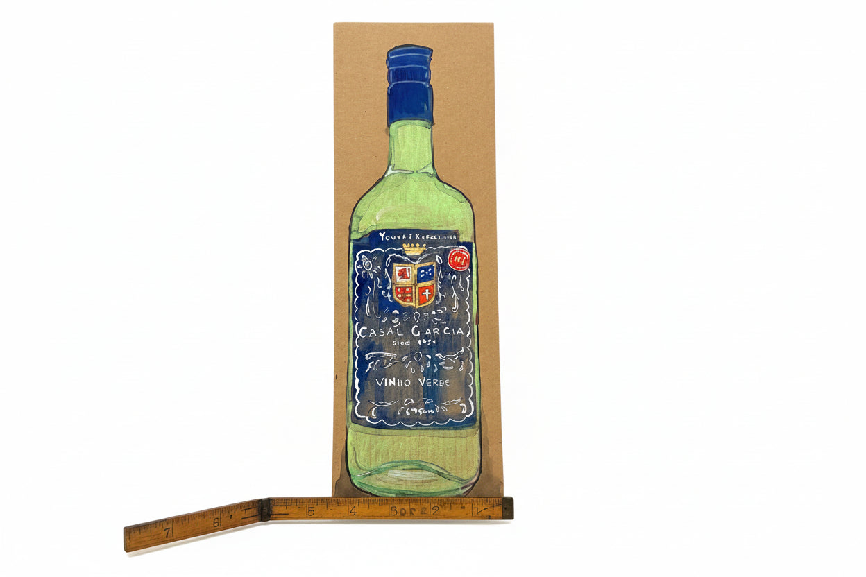 A hand-drawn illustration of a green wine bottle sits on brown found cardboard, with a diagonal wooden ruler at the bottom left. “Young + Refreshing” by Rachel Nelson showcases Thyne Goods’ unique artistic style.