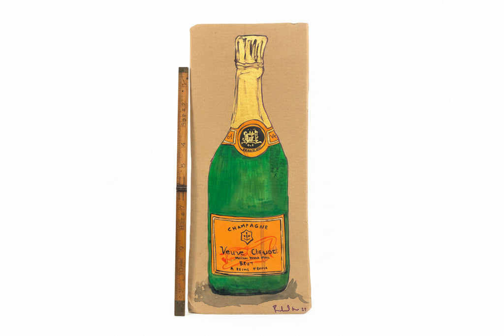 A painted illustration of Thyne Goods Rachel Nelson • Champagne on cardboard is shown next to a wooden ruler for scale, featuring a yellow-orange label and foil.
