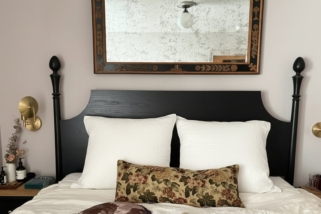 Bedroom with a bed featuring decorative pillows and a large mirror on the wall.