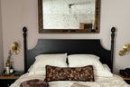 Bedroom with a large mirror above the bed, two wall sconces on either side, and decorative pillows.