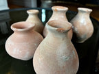 The HomArt Tiny Terra Cotta Vases - Set of 5 features small, round vases with narrow necks and a textured, weathered look. Arranged closely on a dark reflective surface, they showcase handcrafted charm for your decor.
