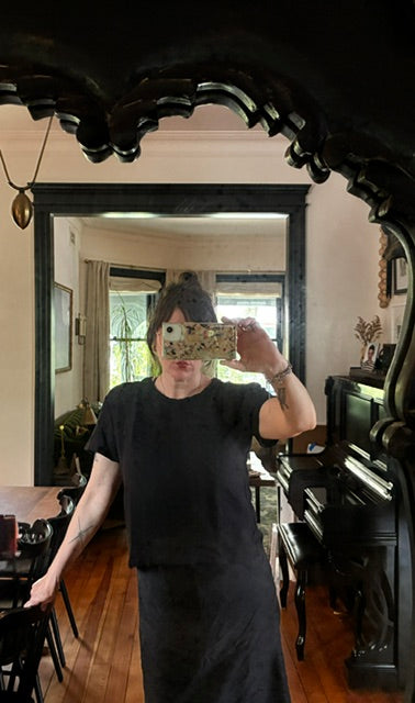 Person taking a mirror selfie in a room with wooden floors and decorative elements.