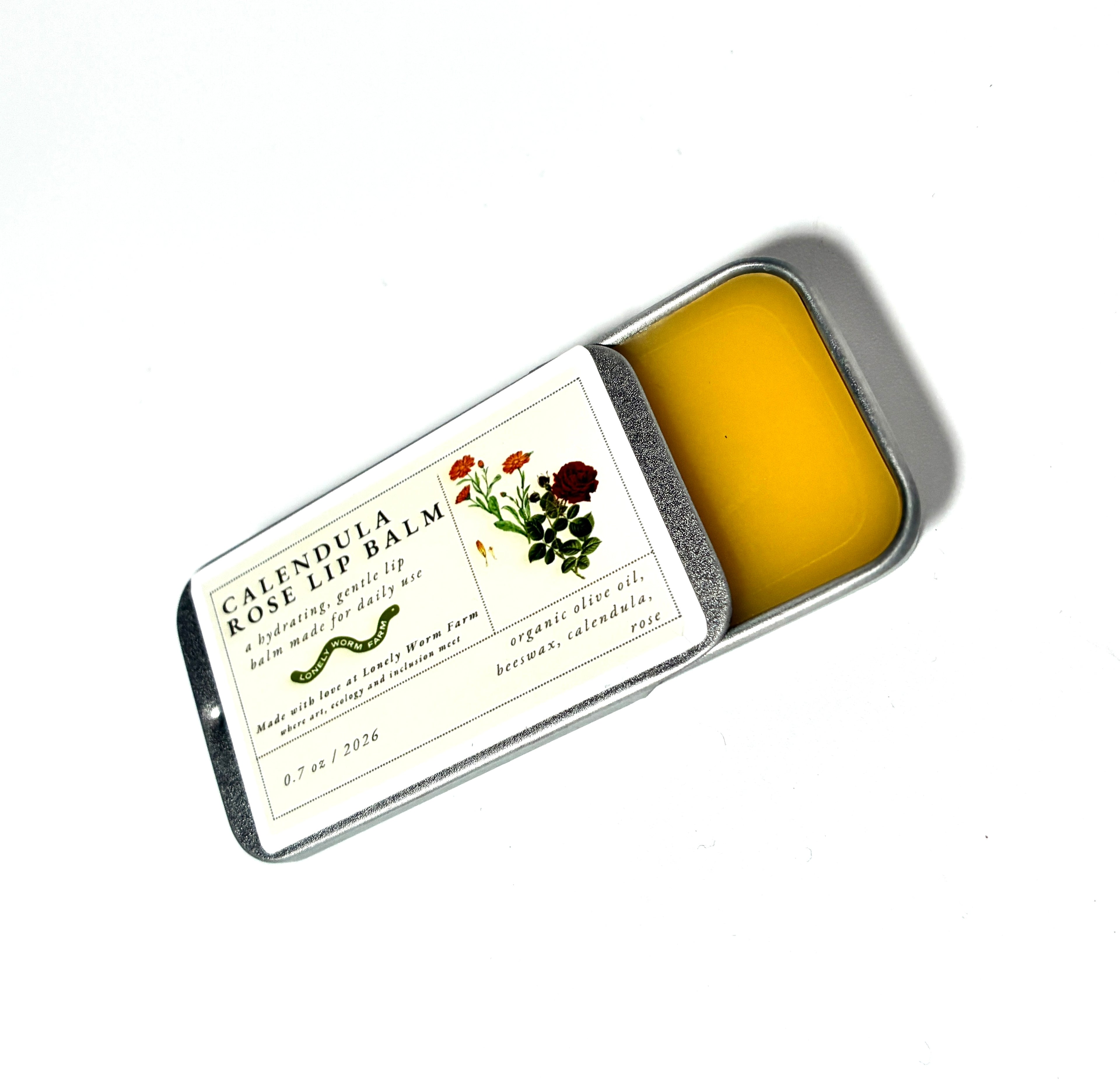 A tin of Thyne Goods’ Calendula Rose Lip Balm from Lonely Worm Farm with a sliding lid, adorned with flower illustrations and product details on the label. Made with organic olive oil and beeswax, this balm gently nourishes your lips.