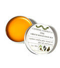 A metal tin filled with Cayenne, Comfrey, and Pine Balm from Lonely Worm Farm by Thyne Goods sits with its lid partially off to the side. The product label lists the ingredients of this soothing chest and muscle balm.