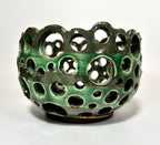 Introducing “Lettuce” by BMB: a green ceramic airplant bowl featuring numerous circular holes of varying sizes across its surface, creating an open and airy design. This handmade clay vessel is both functional and sculptural.