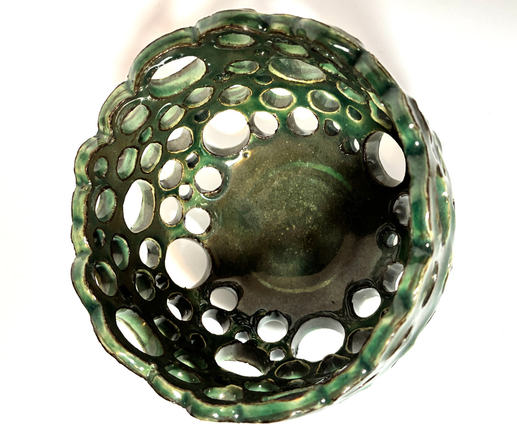 Introducing “Lettuce” by BMB—a green ceramic bowl featuring multiple round holes of varying sizes across its sides and bottom, forming an open, abstract design. This unique handmade clay vessel is ideal as an airplant bowl and is personally signed by the artist for a distinctive touch.