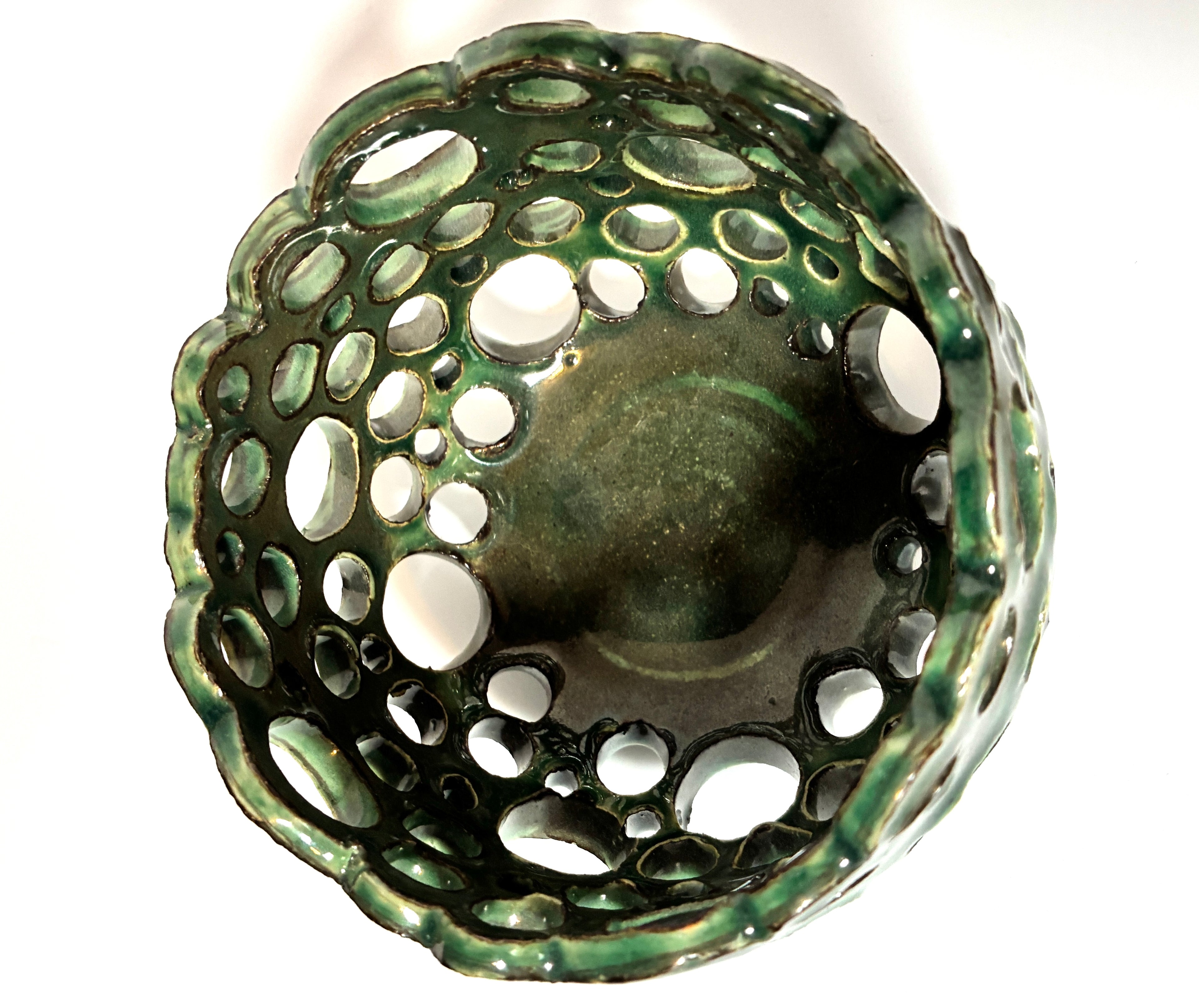 Introducing “Lettuce” by BMB—a green ceramic bowl featuring multiple round holes of varying sizes across its sides and bottom, forming an open, abstract design. This unique handmade clay vessel is ideal as an airplant bowl and is personally signed by the artist for a distinctive touch.