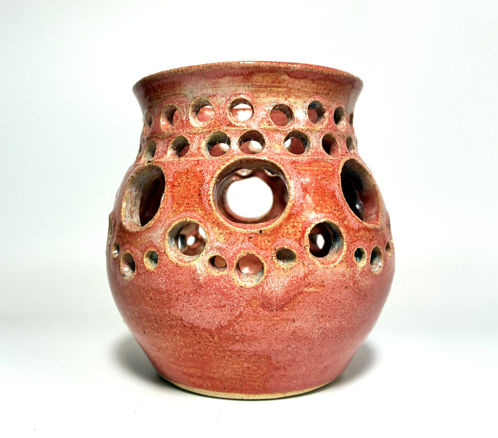 A ceramic vase named “Spam” by Thyne Goods, crafted from clay with a glossy red finish and featuring multiple round holes of varying sizes across its body, is displayed against a plain white background.