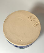 The base of the unique, handmade clay vase is inscribed with “BMB” on its unglazed bottom. The piece features a smooth, rounded surface and evident hand-crafted details, indicating it is likely the distinctive “Widow’s Bay” vase by BMB.
