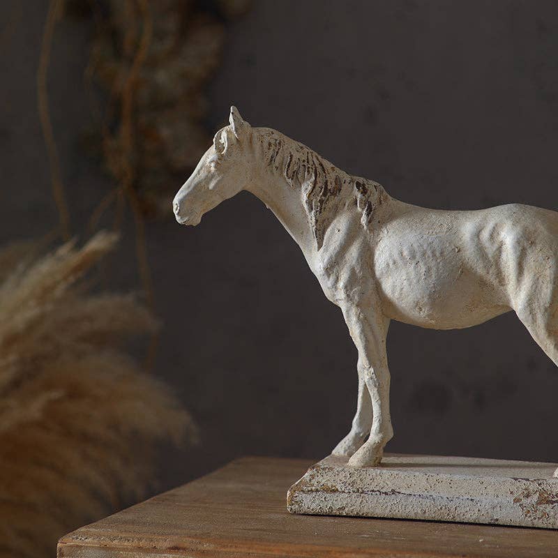 The Rustic Horse Sculpture by Vagabond Vintage features a textured, off-white horse on a rectangular base—ideal for farmhouse decor and styled with dried grasses against a moody backdrop.