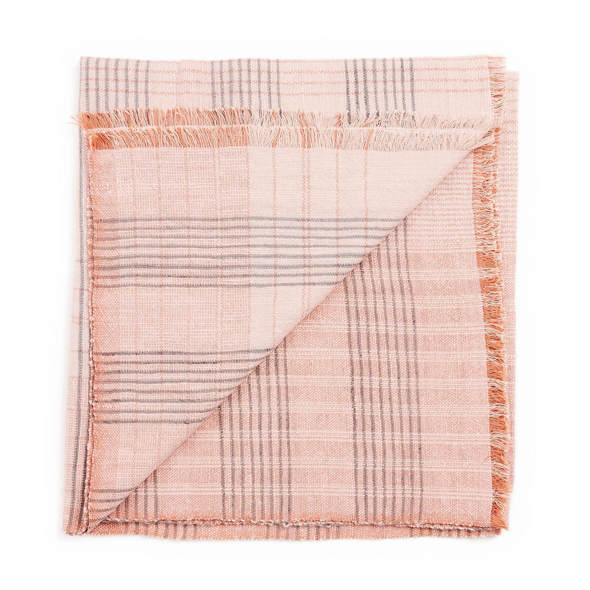 A Silica Rose Throw by Variously, featuring shades of salmon and gray in a stripes pattern, neatly folded with one corner flipped over to show both sides of the fabric.