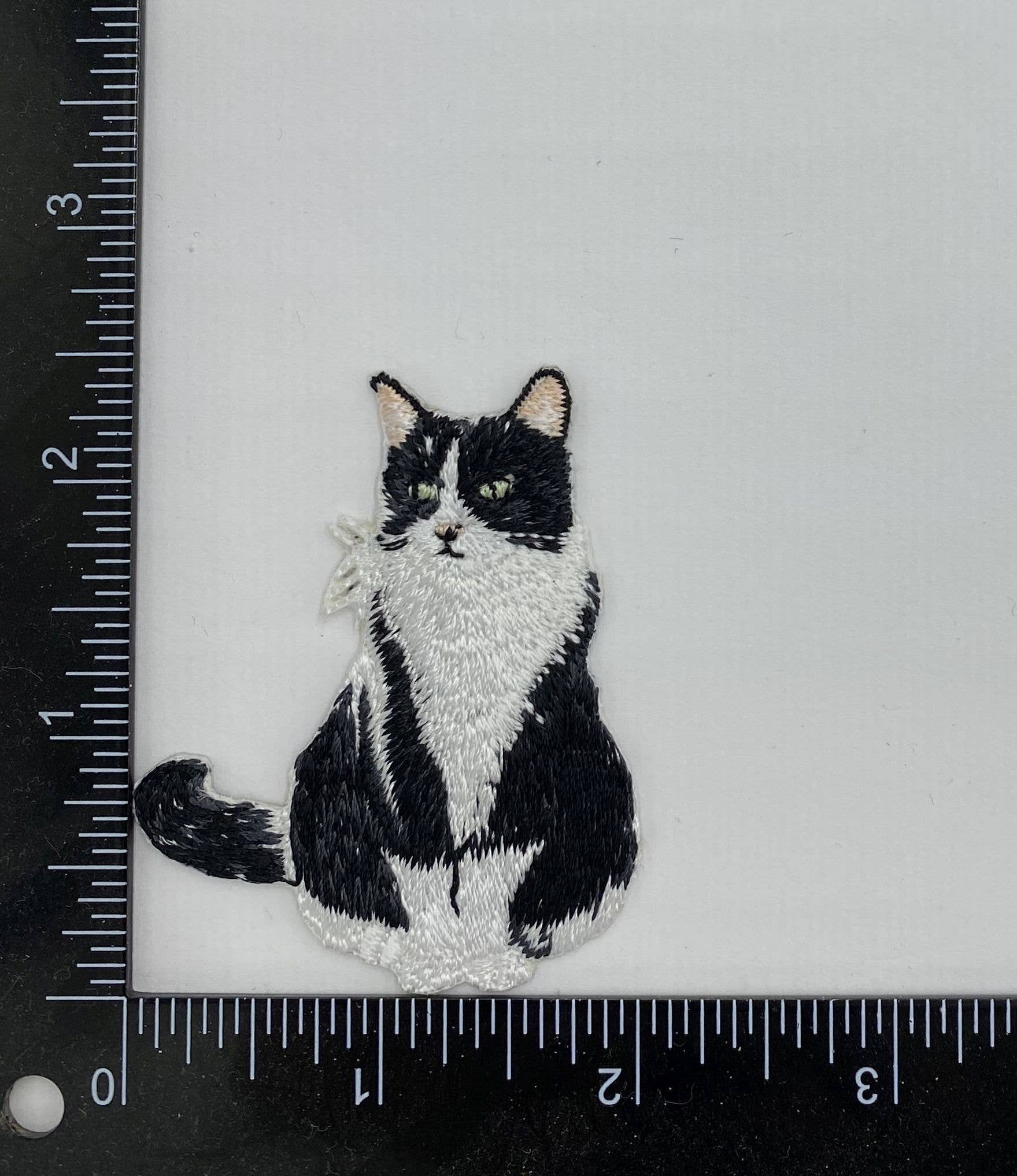 A Wholesale Applique Tuxedo Cat Kitten Pets iron on patch is displayed on a white surface beside a black ruler, showing the patch measures approximately 2 inches tall by 1.5 inches wide.