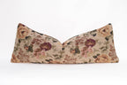 The Tapestry Long Lumbar pillow by Twenty Third by Deanne features a decorative jacquard floral pattern in brown, pink, green, and beige on a plain white background.