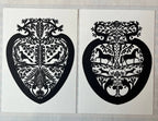 Parcel’s Papercut Heart Art Cards feature two 5x7 black heart-shaped designs with symmetrical birds, deer, and leaves. Displayed side by side on a grid-patterned background, each comes with a creamy white envelope.