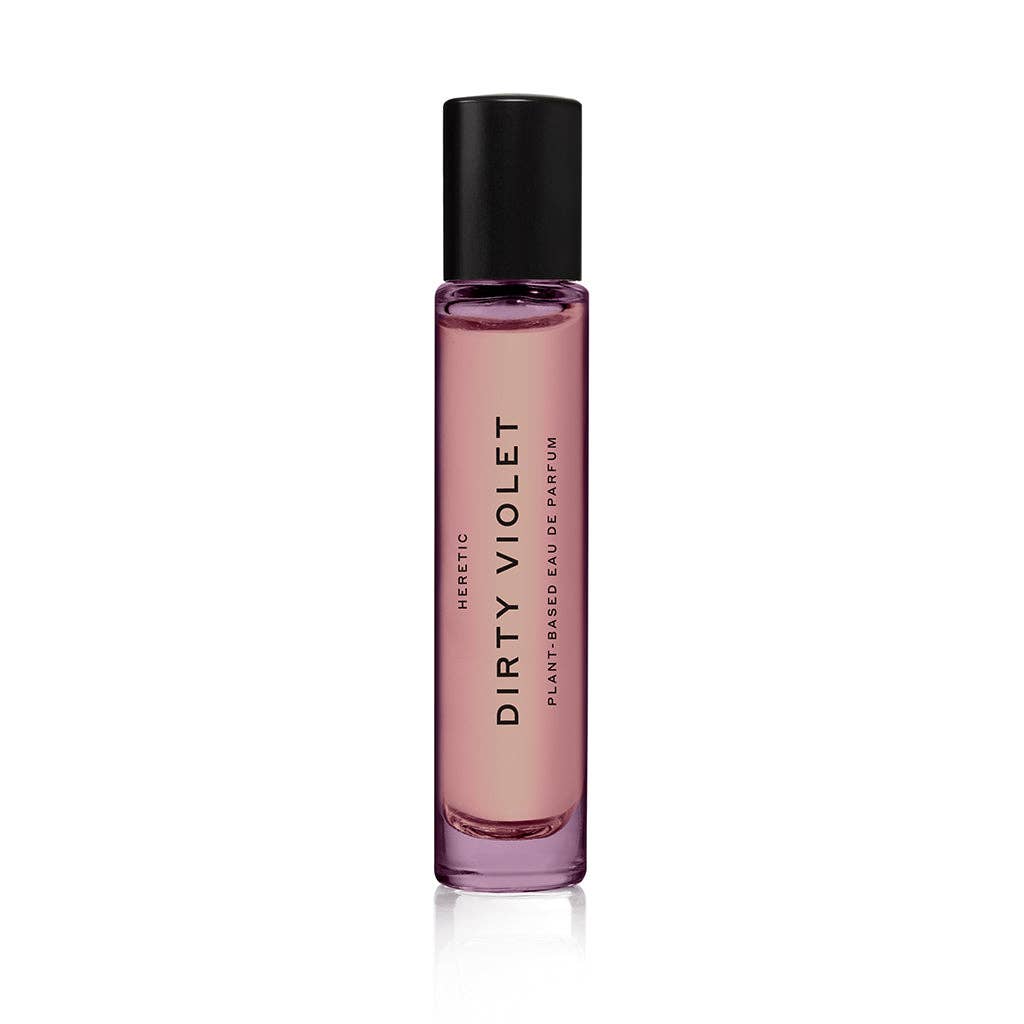 A purple glass perfume bottle with a black cap, labeled "Heretic Parfum DIRTY VIOLET: 15ML" vertically on the front, is photographed against a white background and features notes of violet leaf and amber.