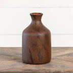The Ragon House 9.75" Brown & Rust Tone Vase, featuring a textured brown finish and slender neck, sits on a wooden surface against a white background.
