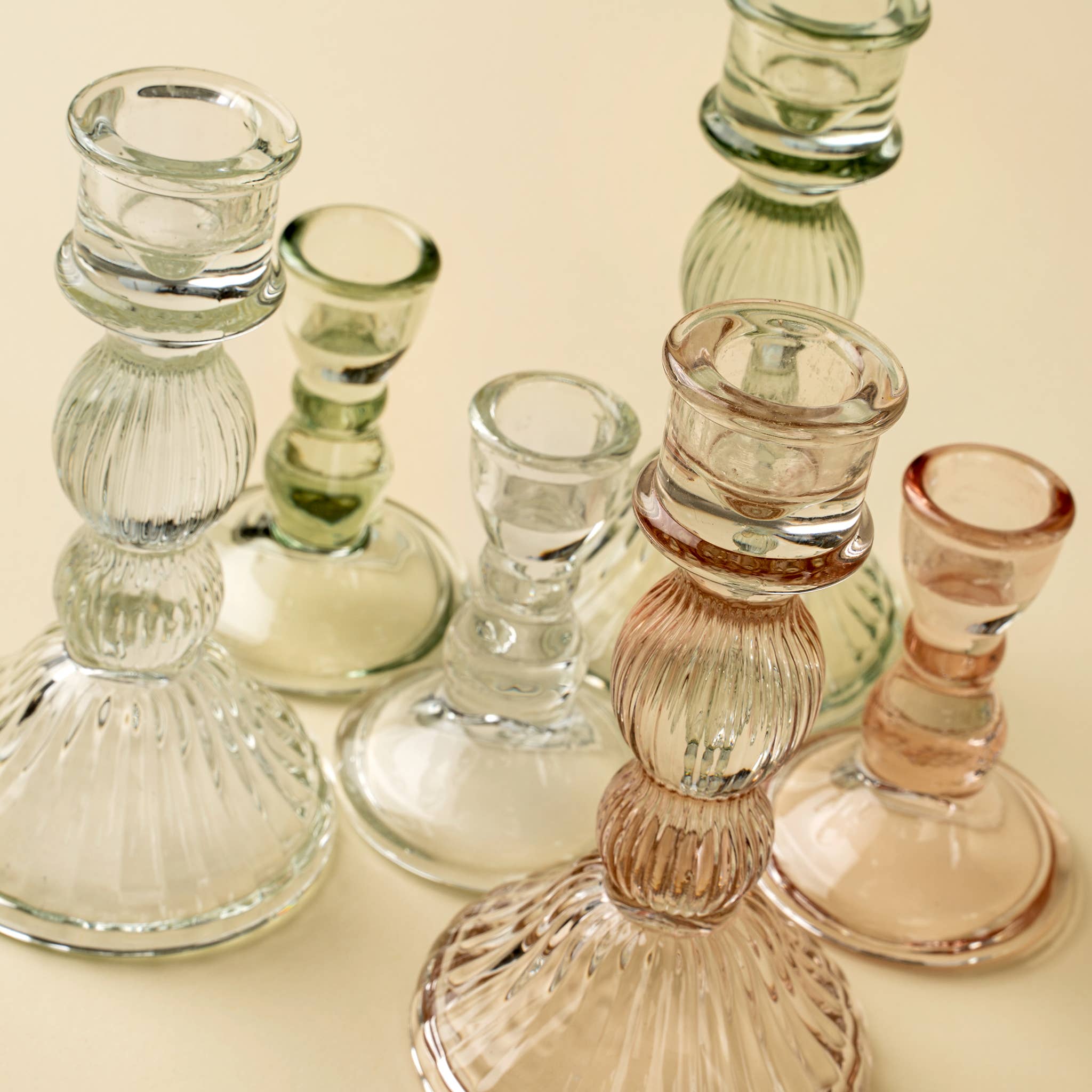 The Indaba Trading Callista Glass Candleholder Large in Blush features elegant ribbed glass in a pastel pink hue, perfect for vintage-inspired decor and adding a stylish accent to any surface.