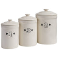 The Park Designs Ironstone Set of 3 Canisters features cream-colored ceramic canisters with lids, labeled 1, 2, and 3 in black decorative font, arranged from shortest to tallest—ideal for storing tea or coffee.
