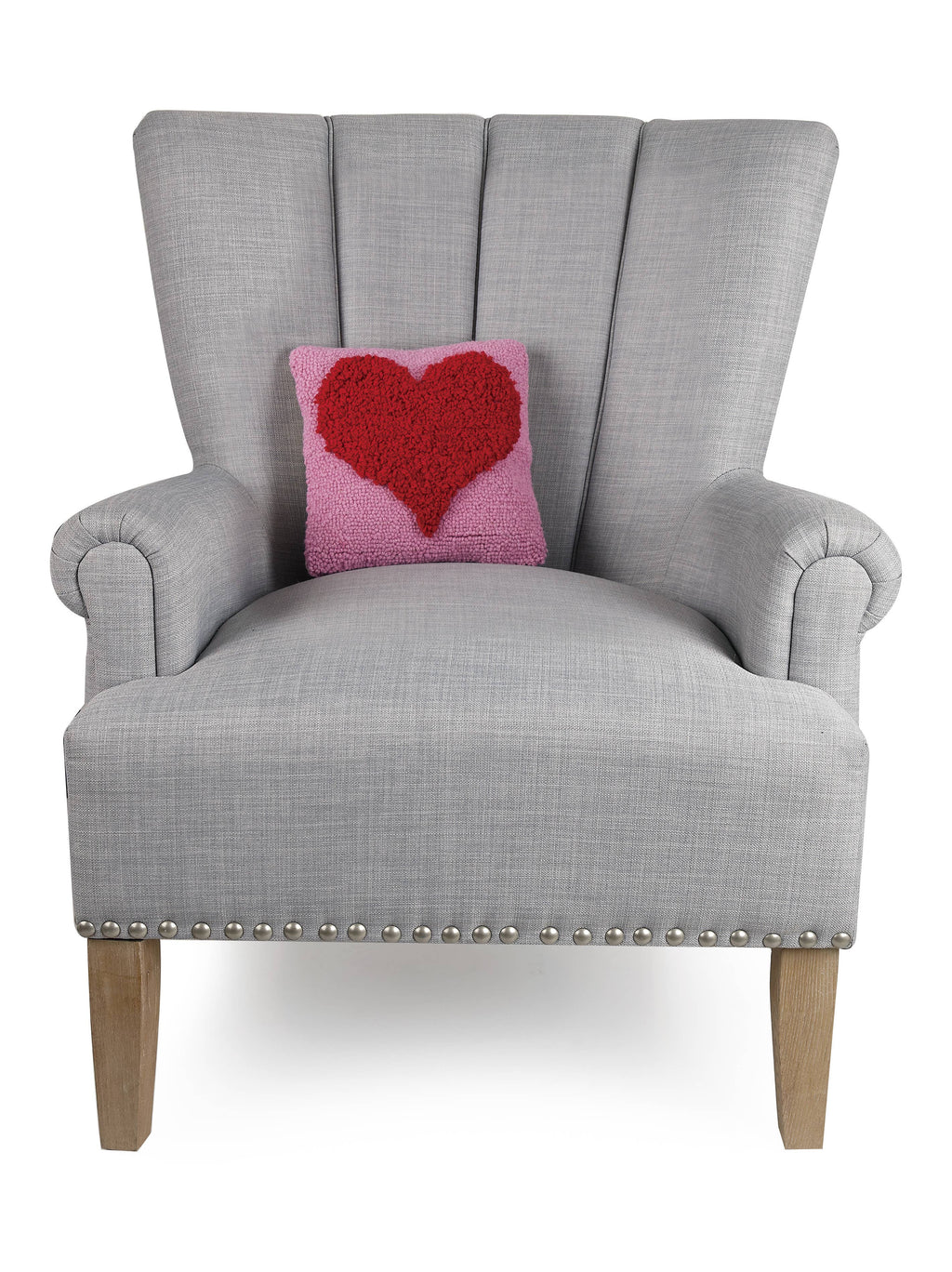A grey chair is adorned with the Peking Handicraft Looped Heart Hook Pillow, adding a cozy, inviting touch.