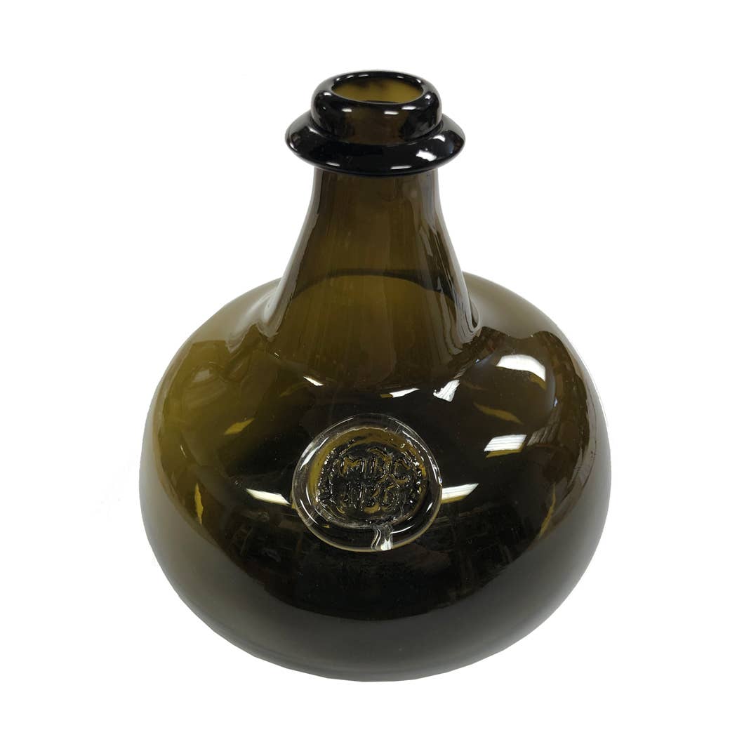 The Madison Bay Co. Hand-Blown Dark Green 76-oz. Onion Bottle (8”) is an antique reproduction with a wide, round body, short neck, flared lip, and comes embossed with a circular seal on the side.