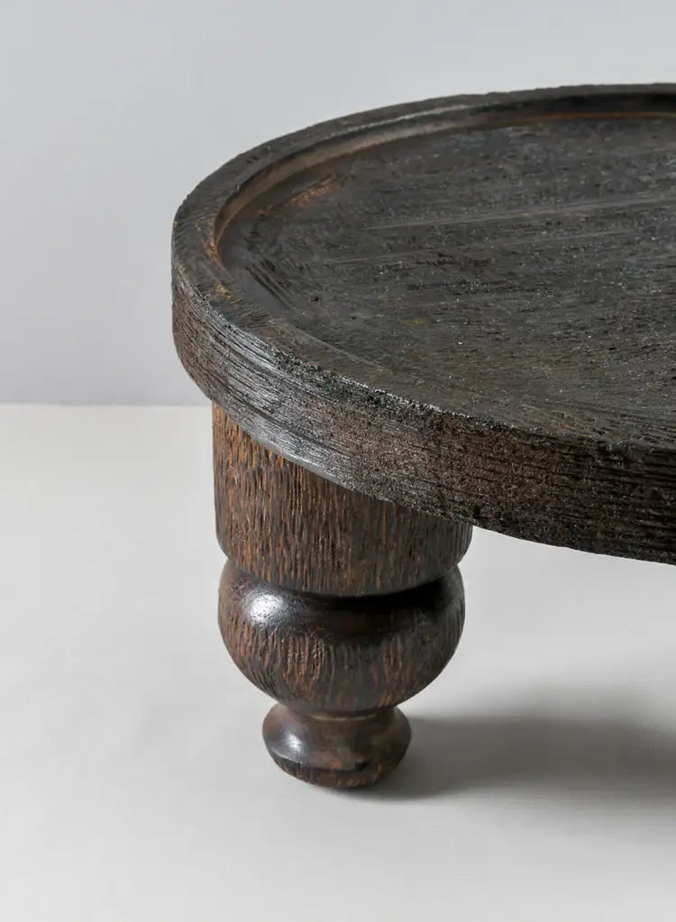 A close-up of the Jamali Garden 14in Wide Banjara Reclaimed Look Deep Brown/Black Rugged Wood Stand, featuring a thick top and sturdy turned leg, set against a plain light-colored background.