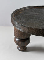 A close-up of the Jamali Garden 14in Wide Banjara Reclaimed Look Deep Brown/Black Rugged Wood Stand, featuring a thick top and sturdy turned leg, set against a plain light-colored background.
