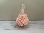 A pale pink Carnation Oaxaca Marigold Day of the Dead Candle shaped like a cluster of layered flowers with a centered wick.