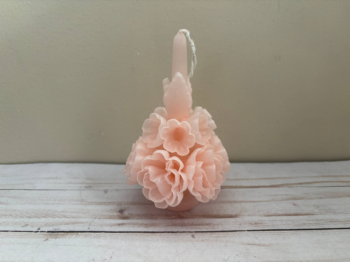 A pale pink Carnation Oaxaca Marigold Day of the Dead Candle shaped like a cluster of layered flowers with a centered wick.